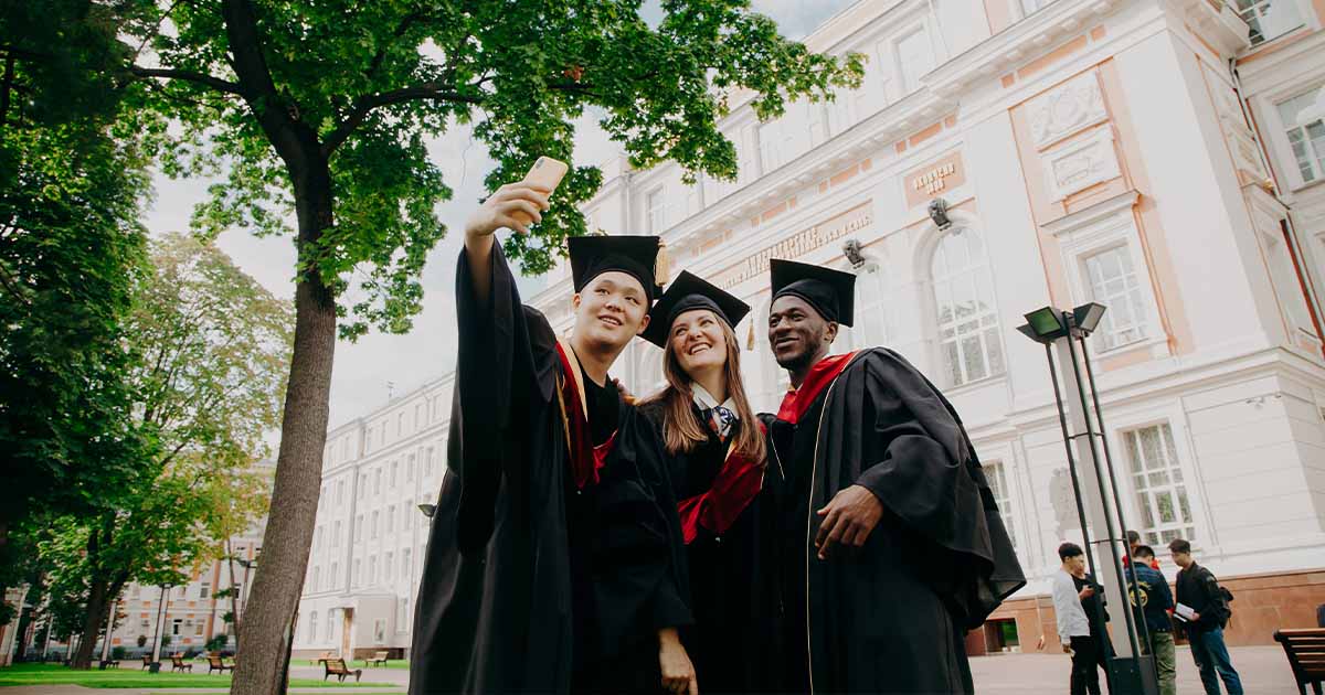 Three international students wearing graduation outfits